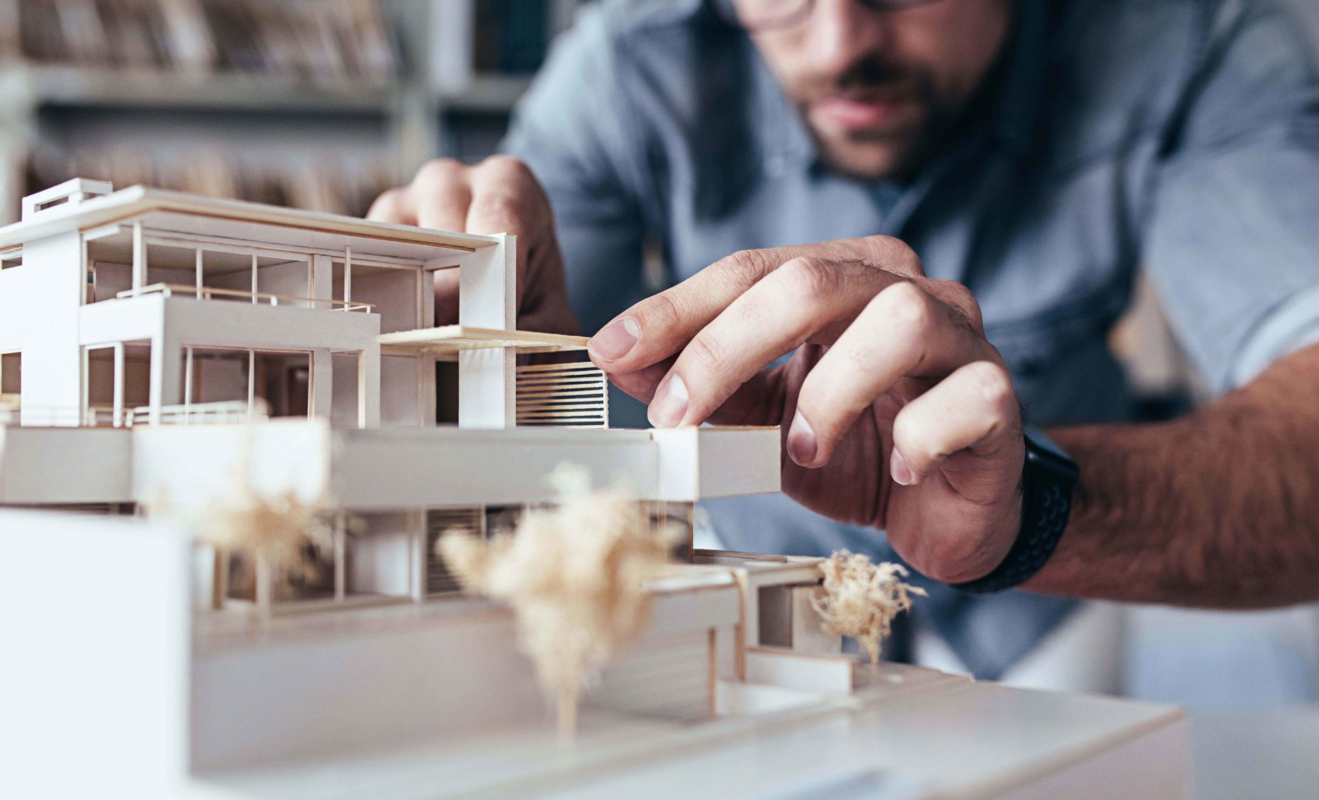Close up of male architect hands making model house. Man architect working in the office.