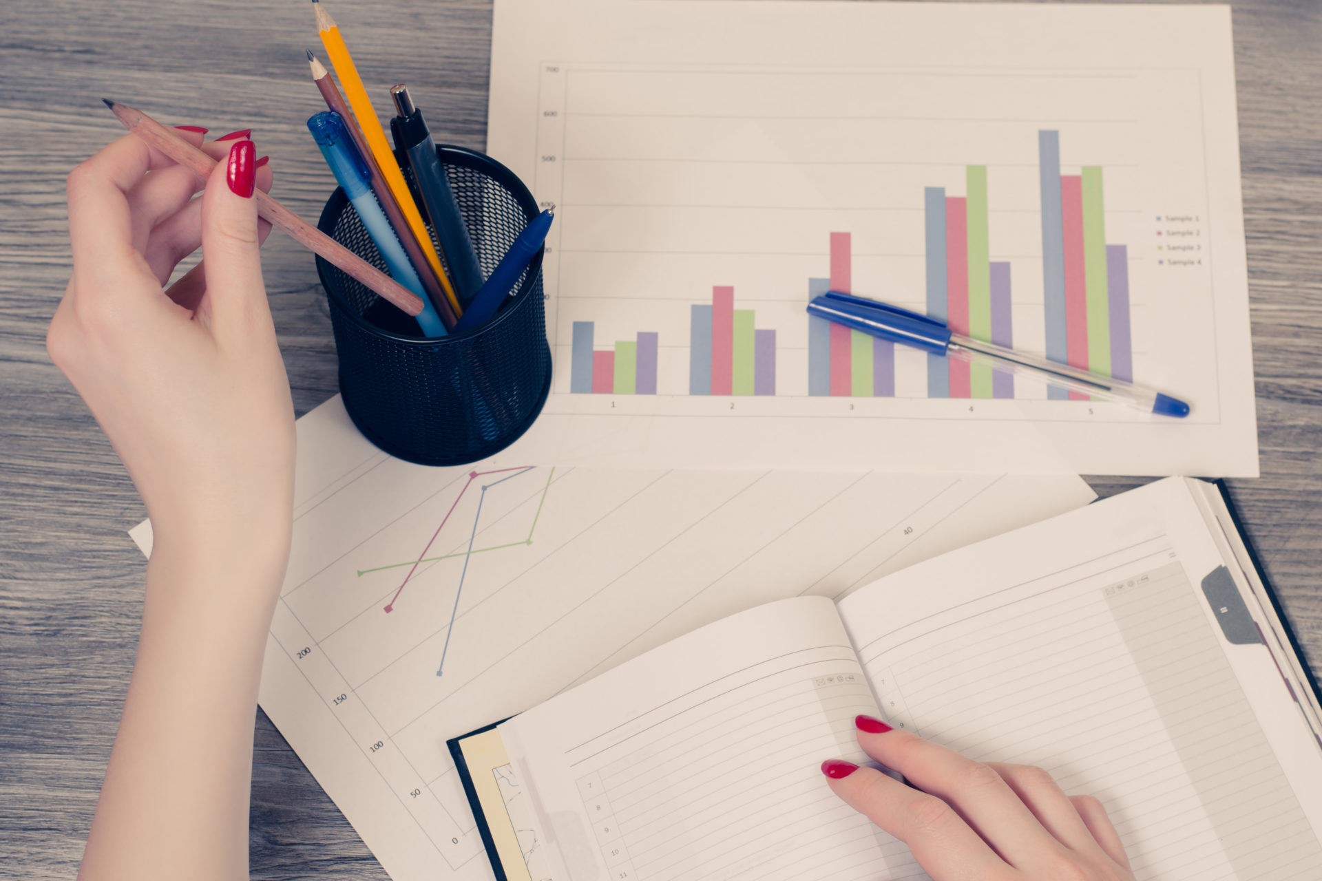 Overhead view of woman's hand taking a pencil from stand for pens and get ready for writing information