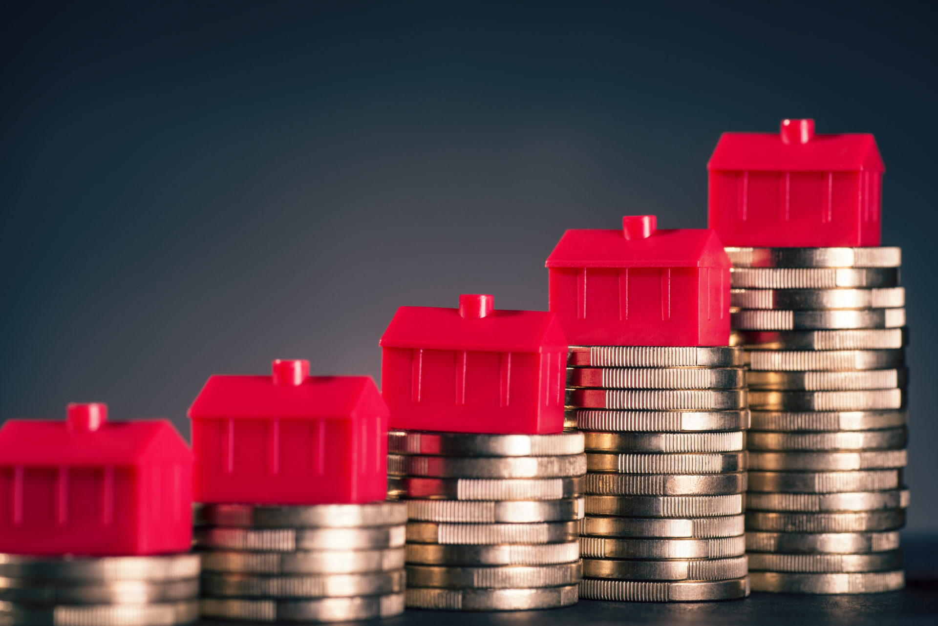 Les petites maisons rouges se tiennent sur des piles avec des pièces de monnaie.