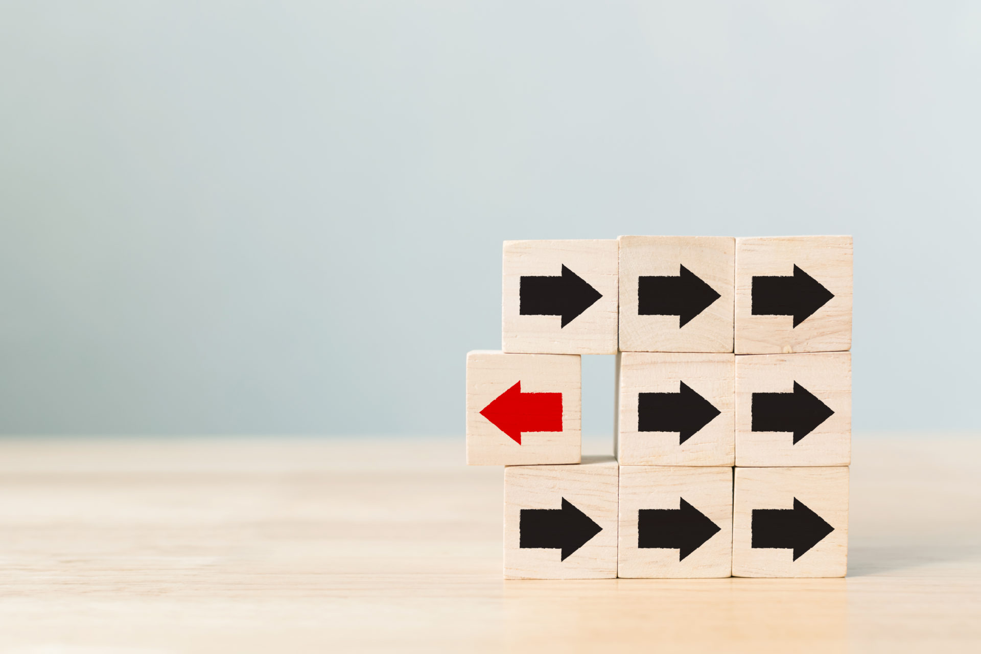 Wooden block with red arrow facing the opposite direction black arrows, Unique, think different, individual and standing out from the crowd concept