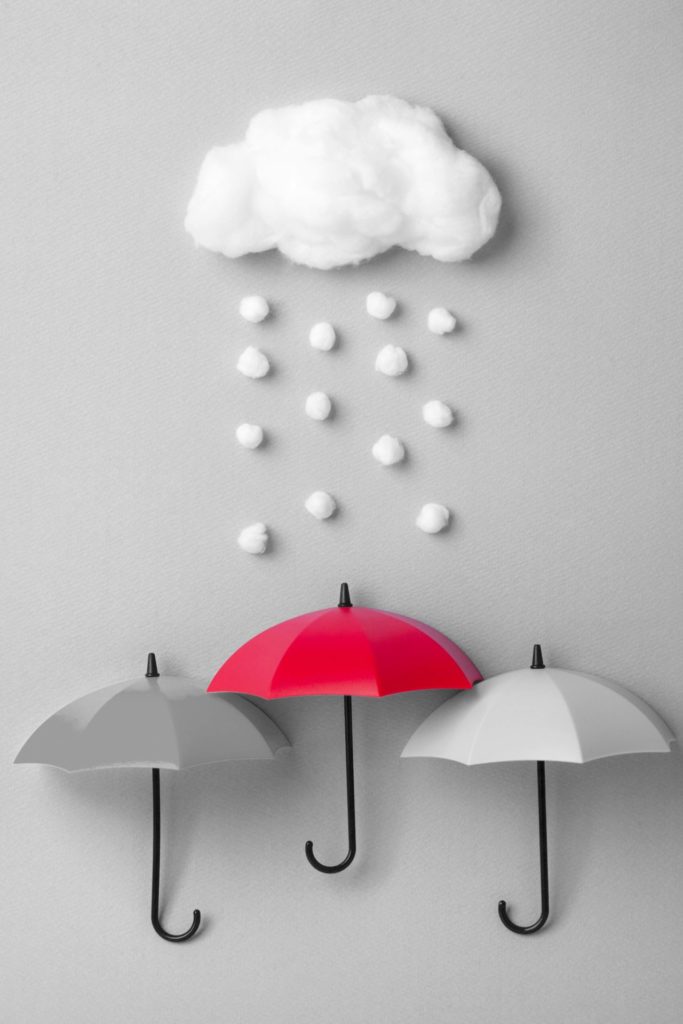 Three umbrellas under the cloud on sky blue background.